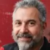 Retrato de hombre sonriente con fondo rojo.