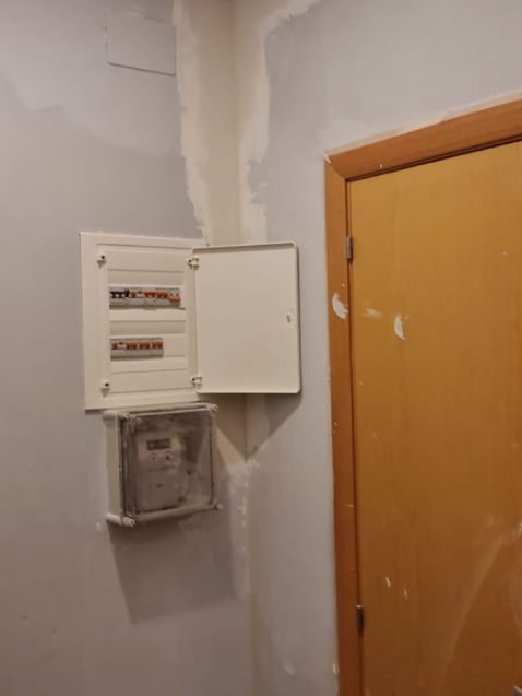 Caja eléctrica abierta junto a puerta de madera.