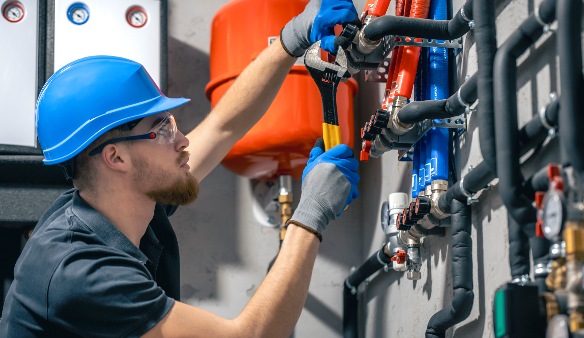 Técnico revisando tuberías industriales con llave inglesa.
