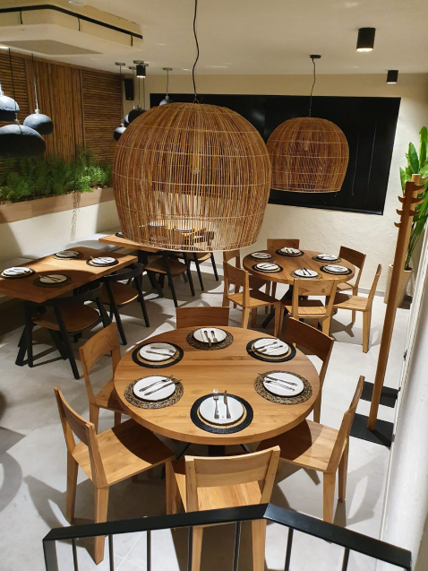 Restaurante moderno con mesas de madera y lámparas grandes.