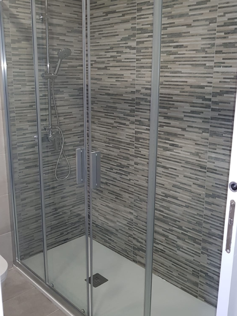 Ducha moderna con azulejos grises y puerta corrediza