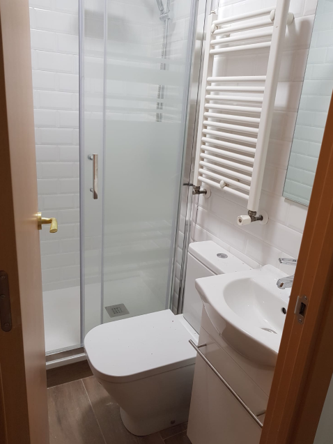 Baño moderno con ducha y lavabo pequeño.