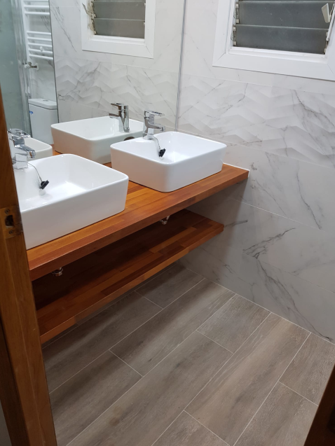 Baño moderno con lavabos dobles y encimera de madera.