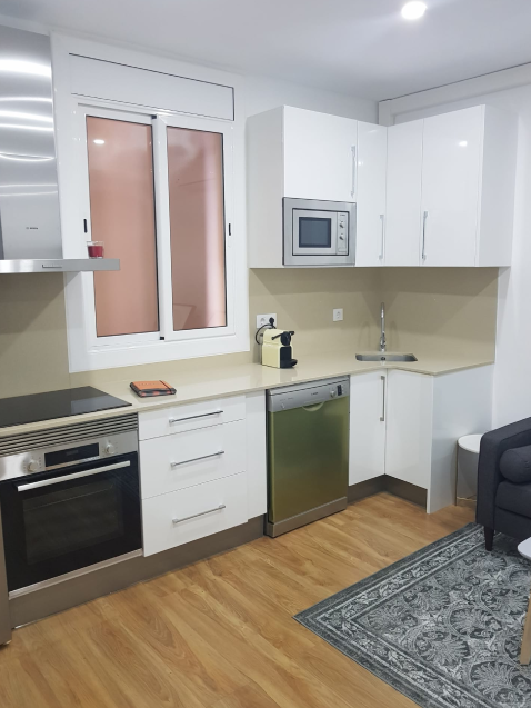 Cocina moderna con electrodomésticos y muebles blancos.