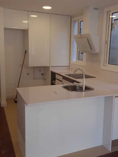 Cocina moderna con armarios blancos y encimera.